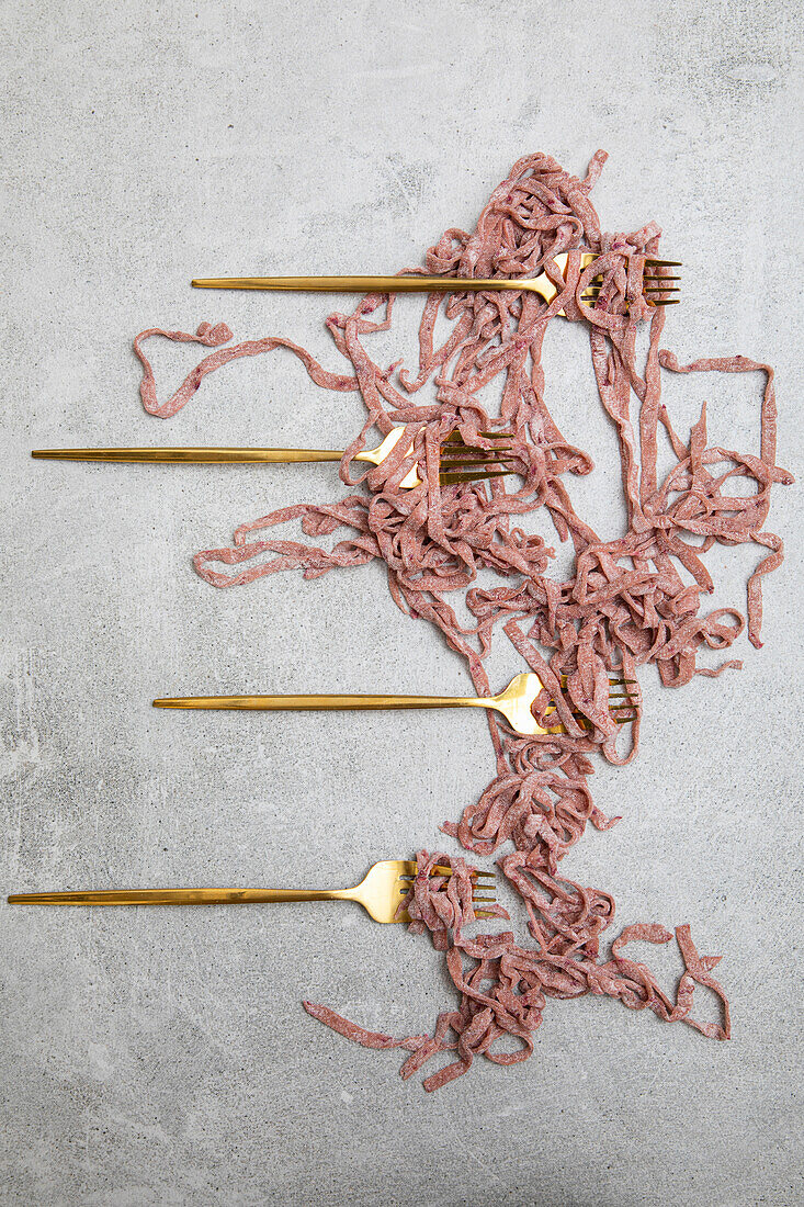 beetroot pasta, with golden forks on a slate background