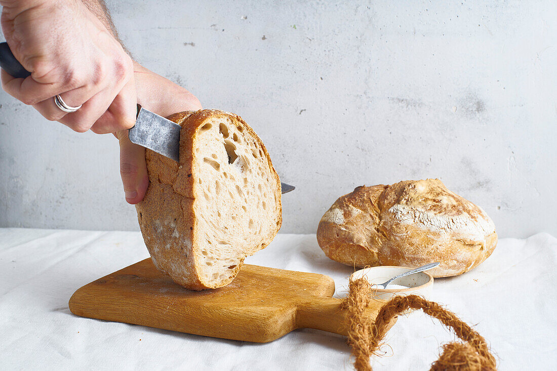 Male hands cutting a loaf of sourdough bread