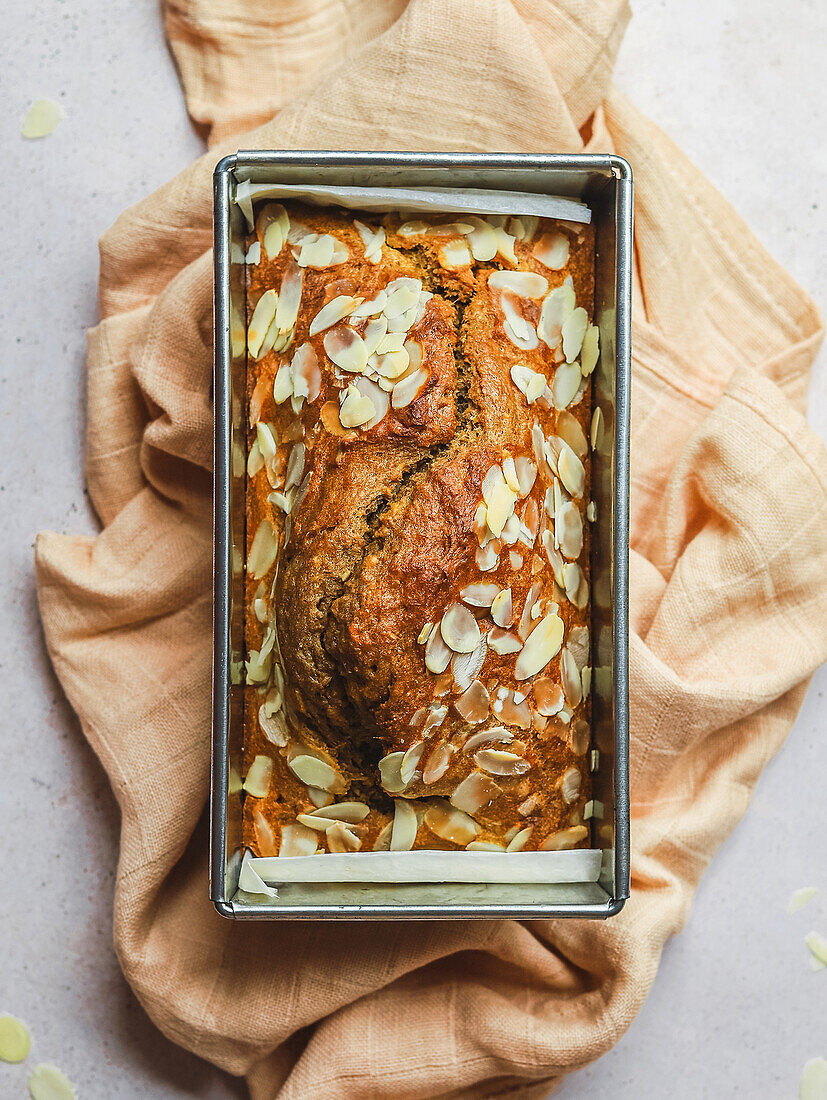 Delicious cake with sweet almond flakes in metal baking from placed on napkin on table