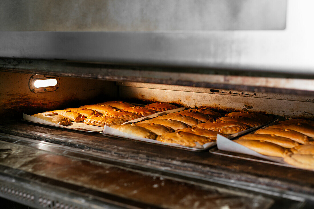 Metal tray with tasty sweet baking placed and preparing in oven in kitchen