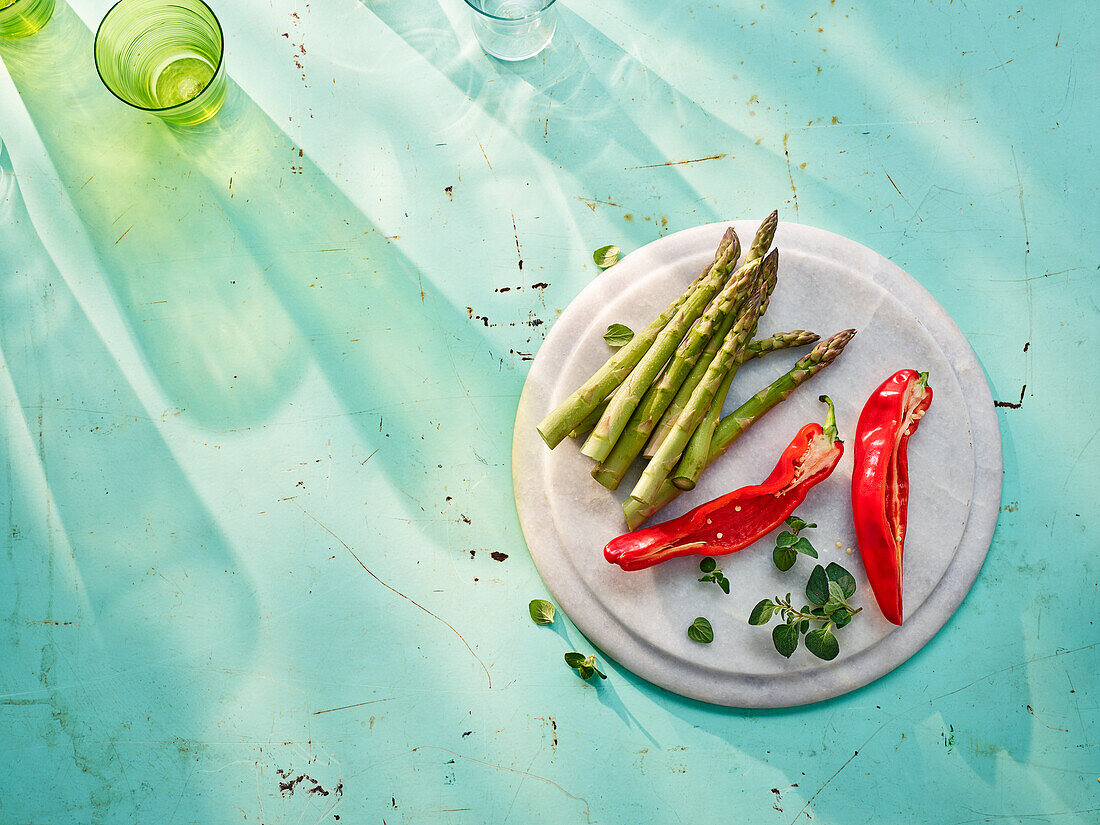 Green asparagus, red chili peppers, and marjoram on chopping board