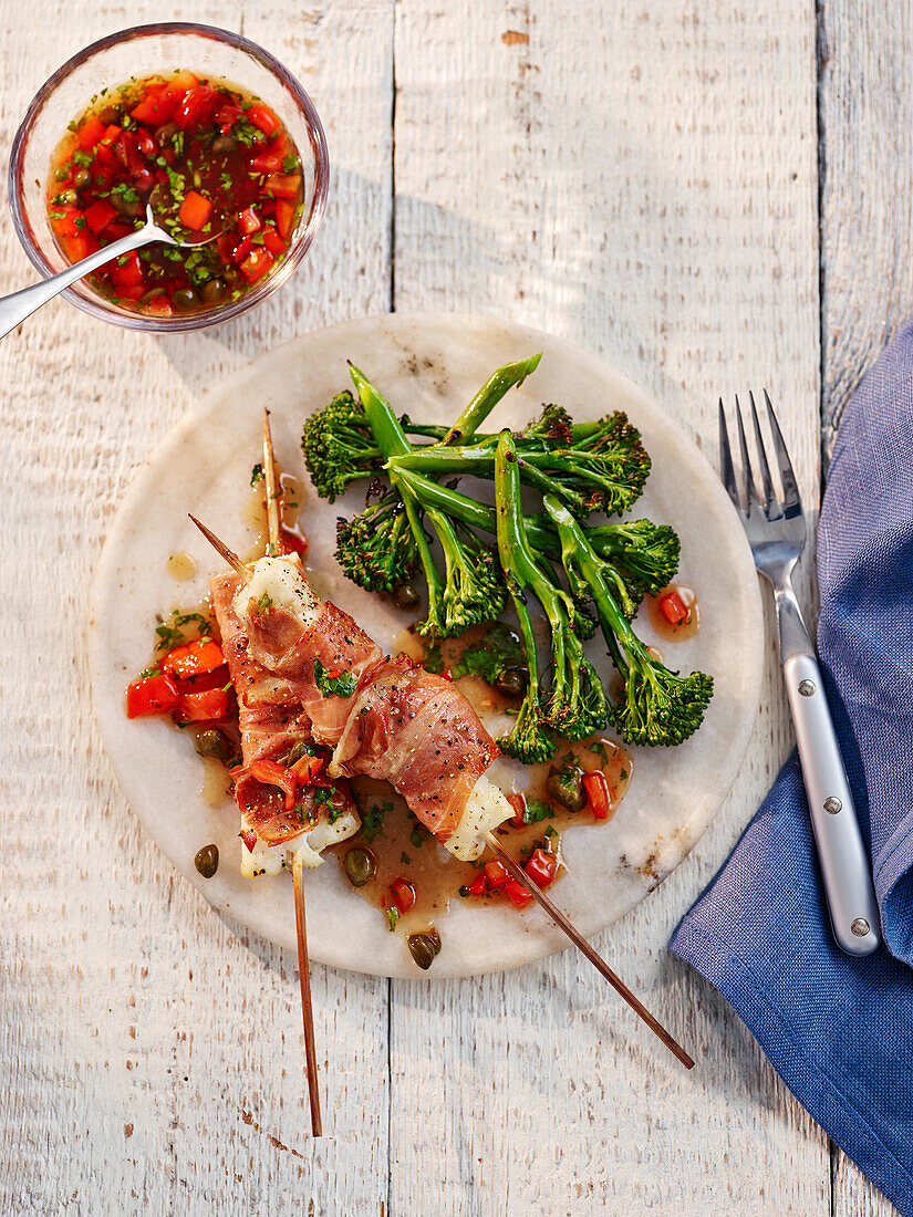 Fish skewers wrapped in prosciutto, with tomato salsa and broccolini