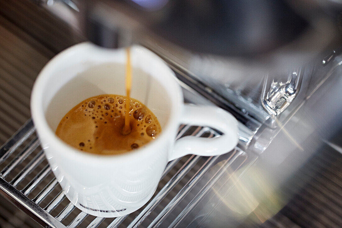 Espresso fliesst aus einer Espressomaschine in eine Tasse