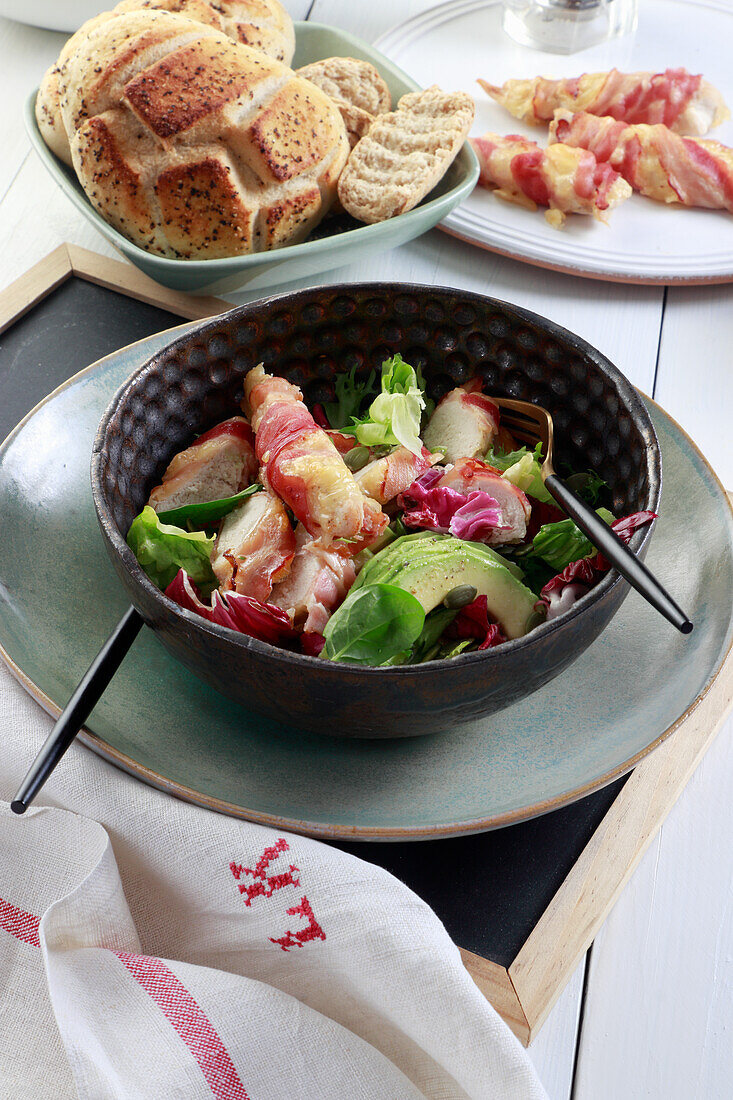 Salat mit Hähnchenbrust in Speckmantel, Avocado und roten Zwiebeln