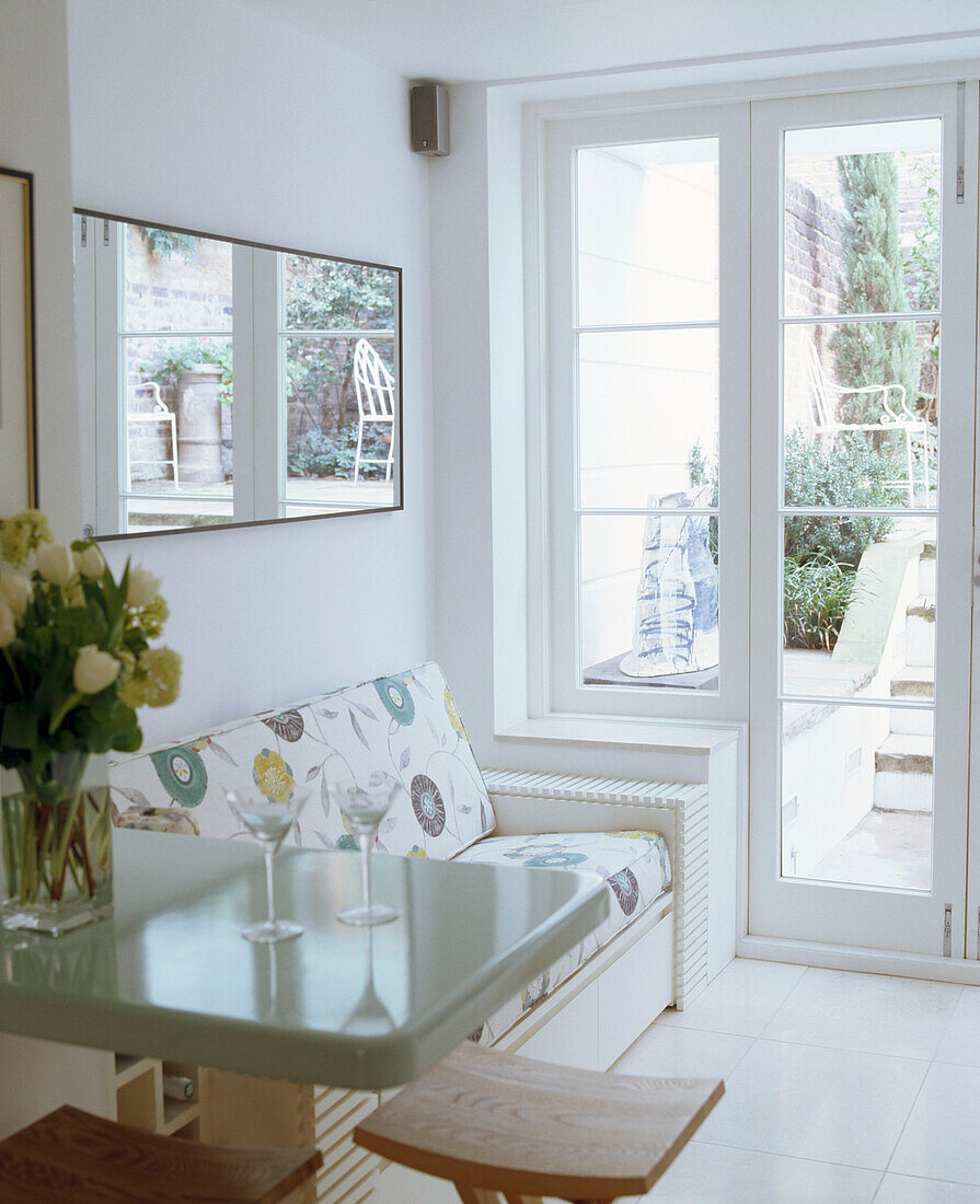 A detail of a modern open plan kitchen with seating area upholstered sofa French windows breakfast bar area stool