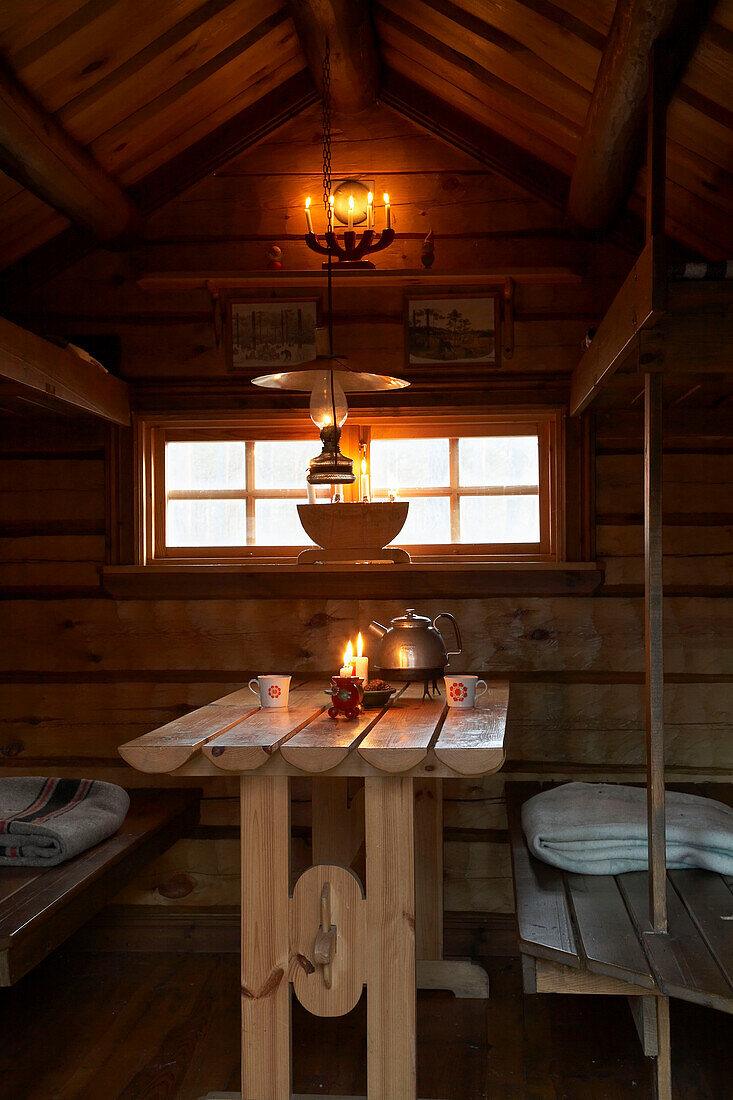 Gegenüberliegende Sitzbänke am Tisch unter dem Fenster in Jagdhütte, Svartadalen, Schweden