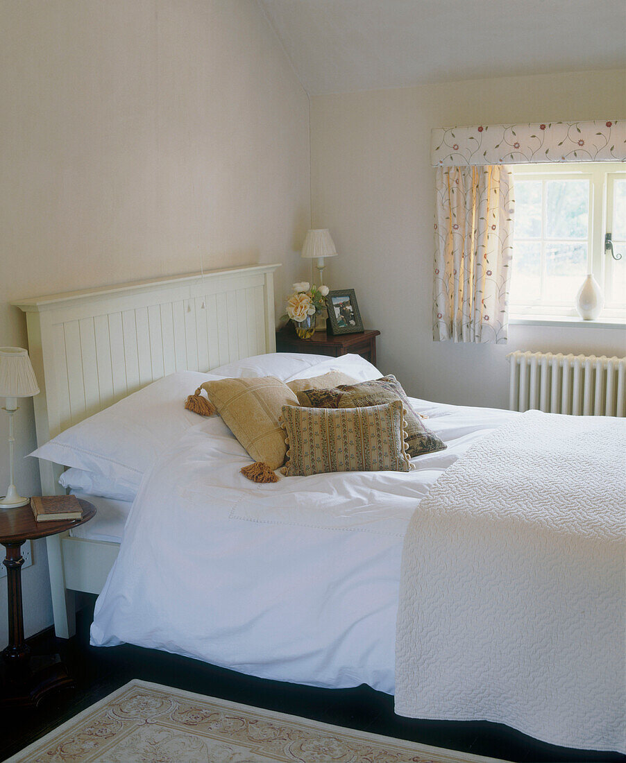 Bed with a wooden headboard by a window in a country style bedroom