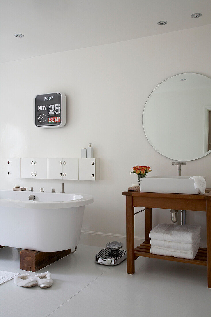 Washbasin on wooden stand next to freestanding bathtub