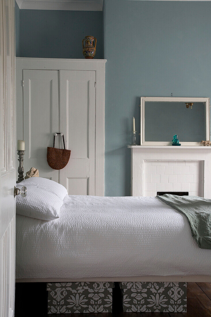 Blick durch die offene Tür auf das Doppelbett vor dem Kamin im blauen Schlafzimmer