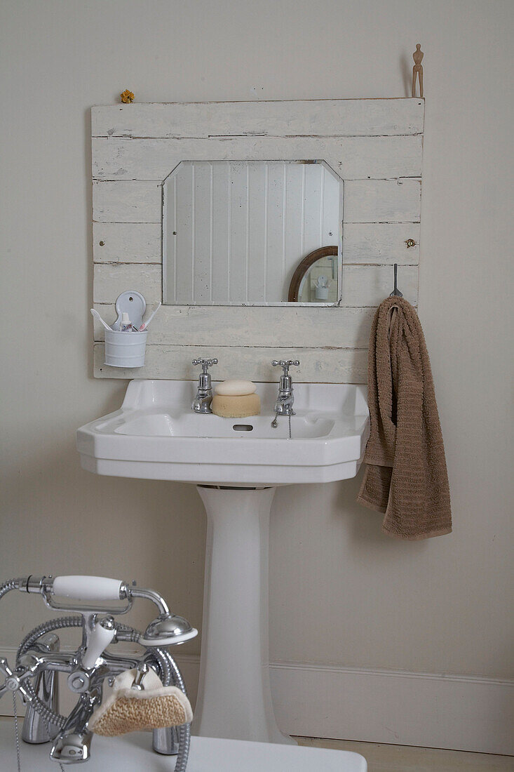 Mirror set on wood panelling above pedestal washbasin