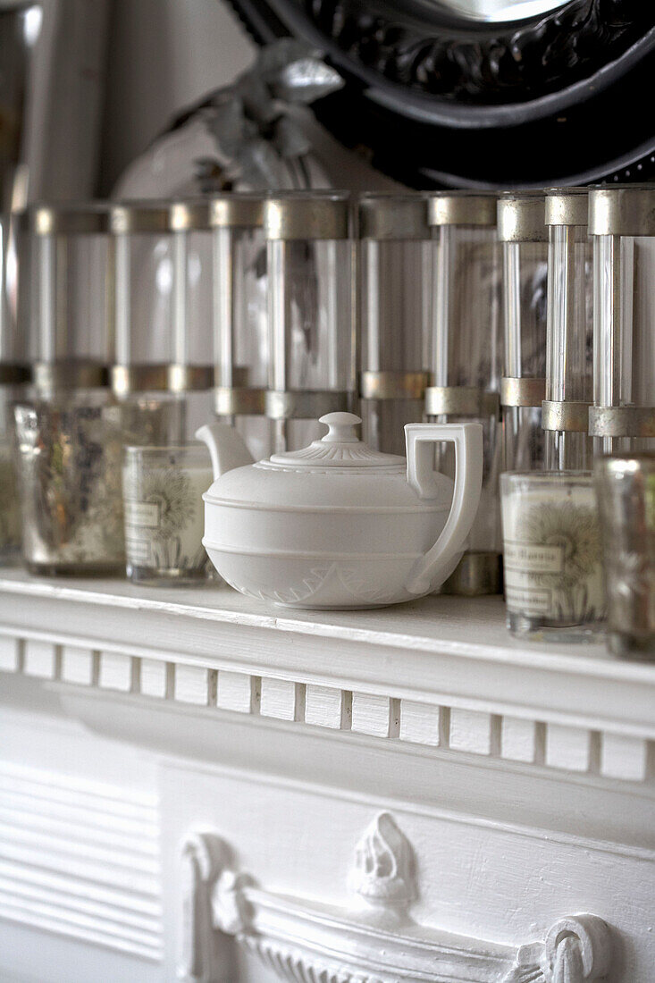 Glassware and pottery teapot on white mantlepiece