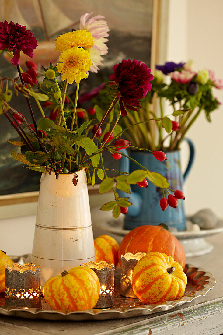 Schnittblumen mit Mini-Kürbis und brennenden Teelichtern in einem Strandhaus in Norfolk, UK