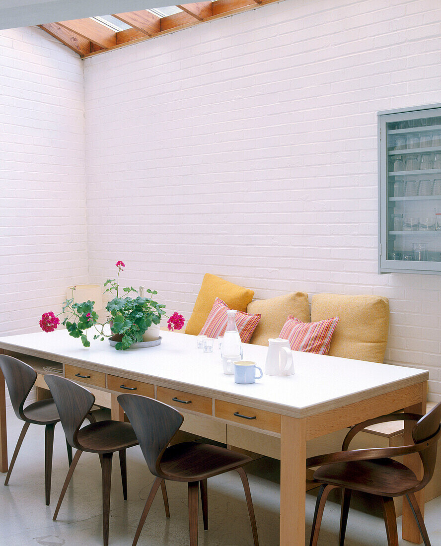 A modern dining room area with a glass ceiling above a large table surrounded by retro styled chairs