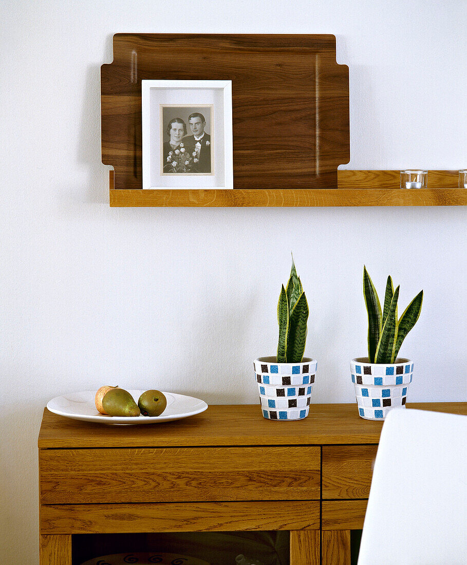 Pot plants and fruit dish on wooden side table