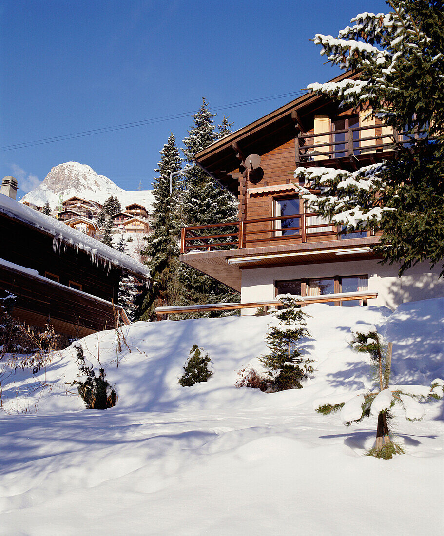 An exterior of a traditional Swiss wooden chalet snow pine trees mountains