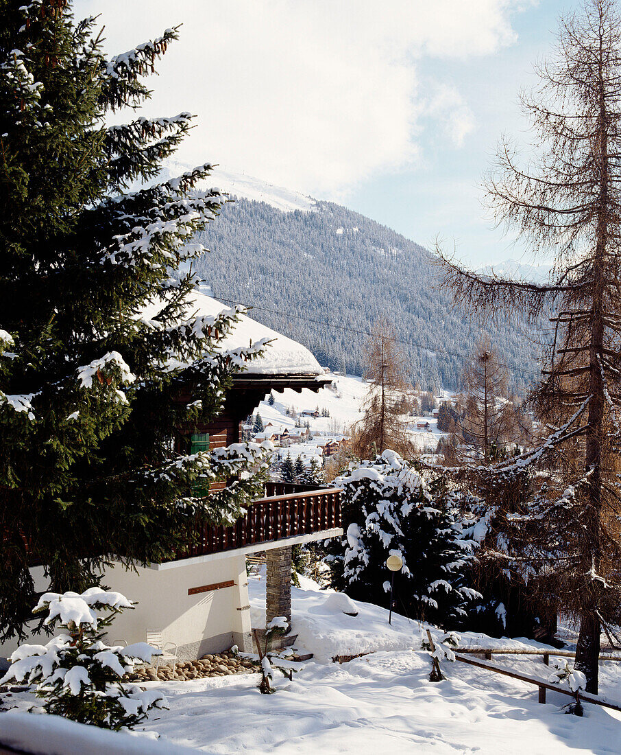An exterior of a traditional Swiss wooden chalet snow pine trees mountains