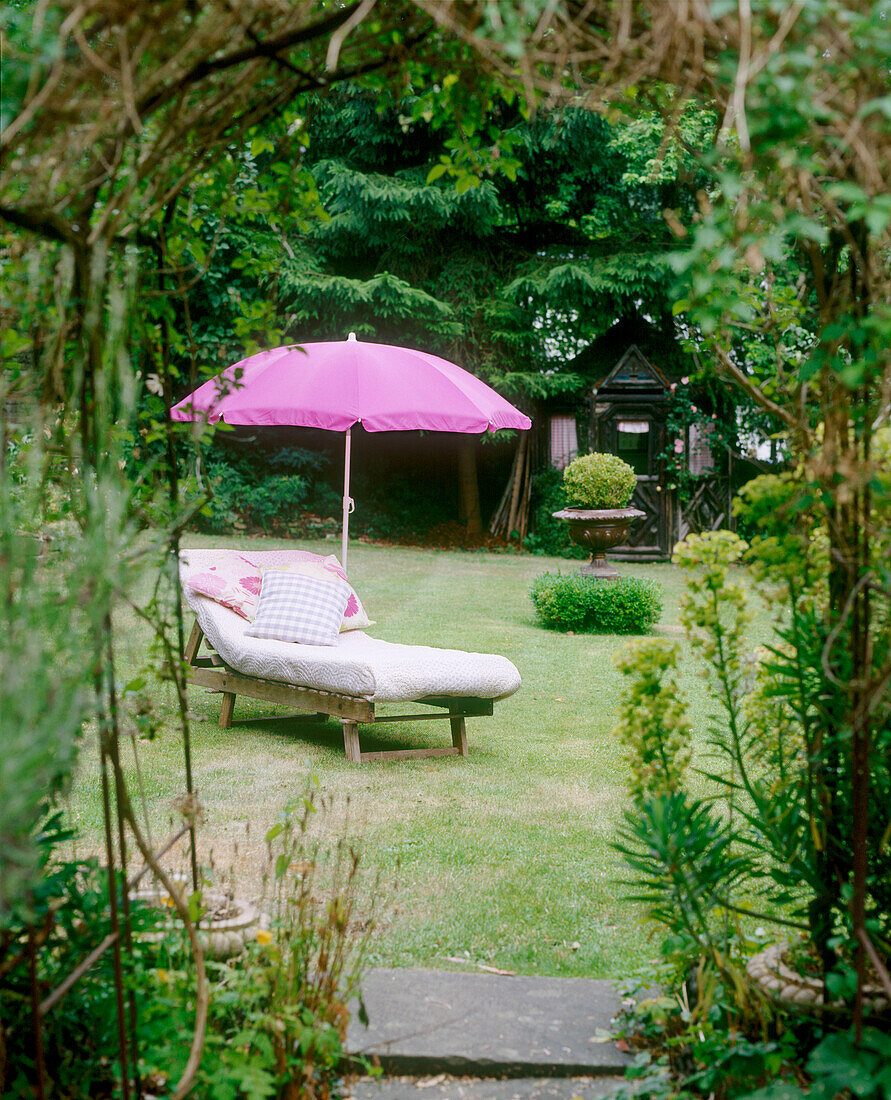 Parasol over sunlounger in country garden