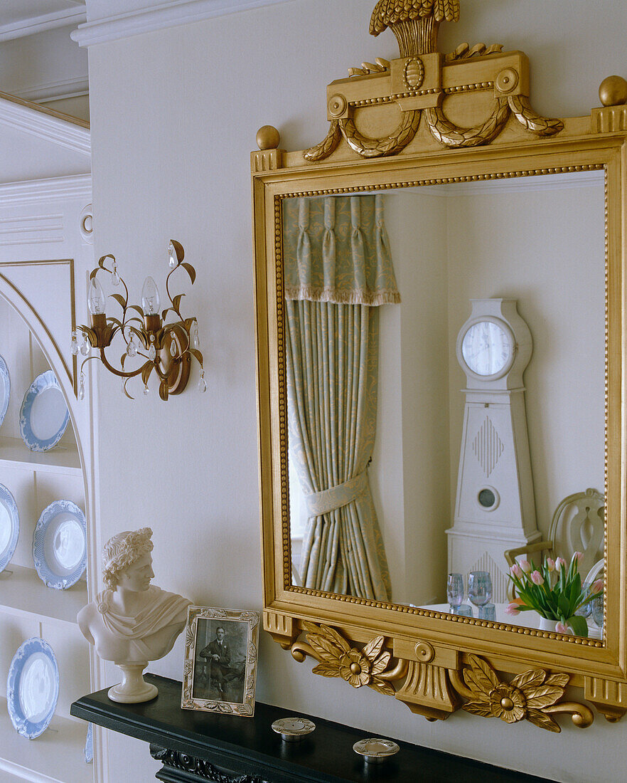 Gustavian clock reflected in mirror in Swedish style dining room