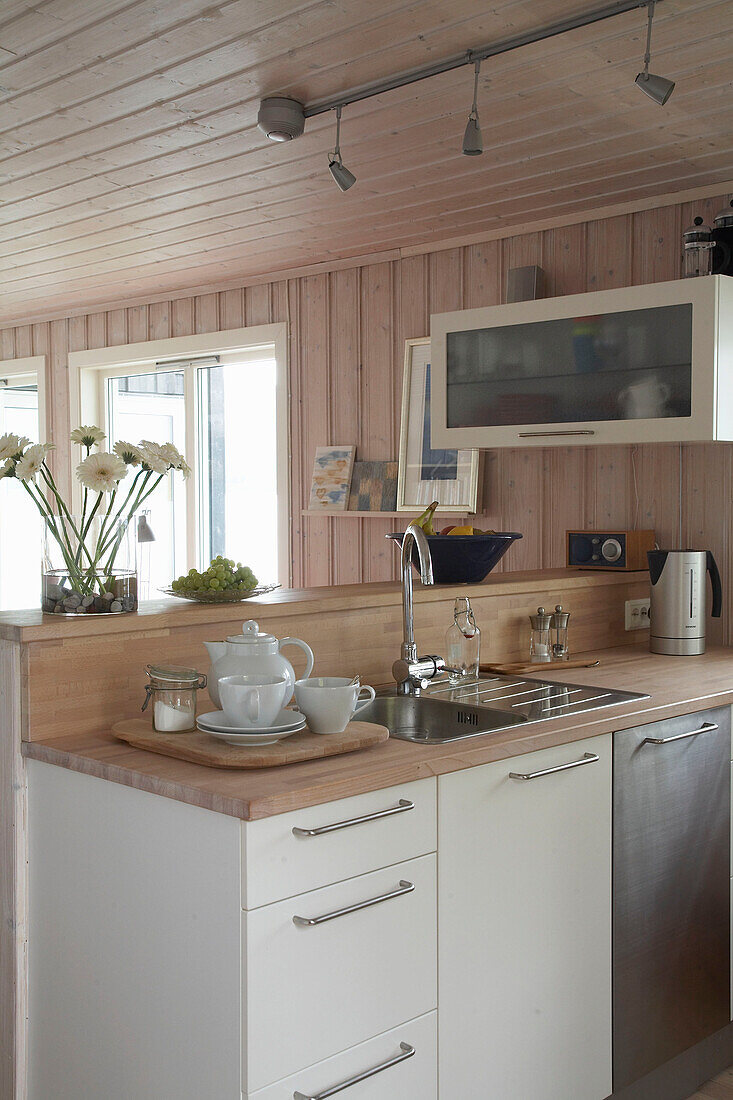 Sink set in wooden worktop on white fitted units in kitchen