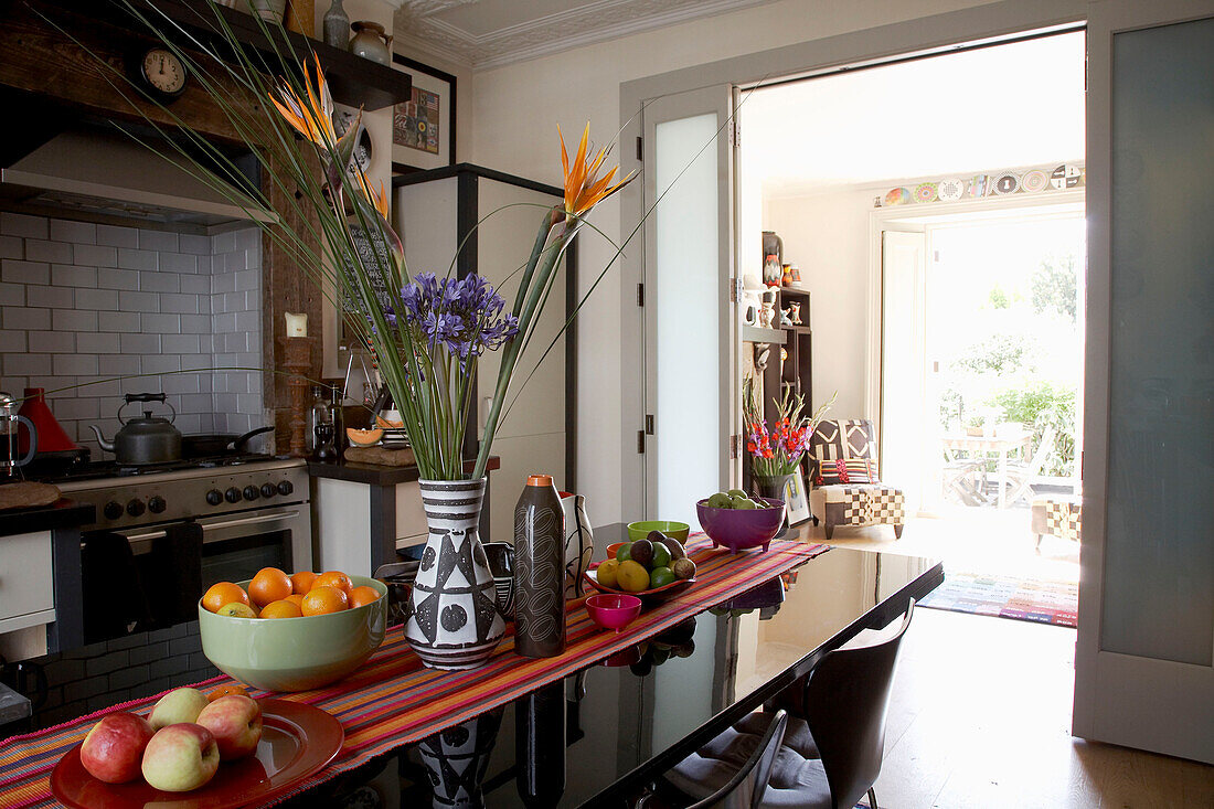 Flower arrangement and bowls of fruit of polished table in contemporary kitchen