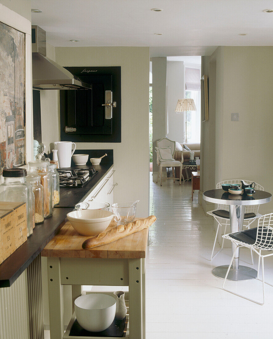 Open plan kitchen with round breakfast table and view through the door to seating room