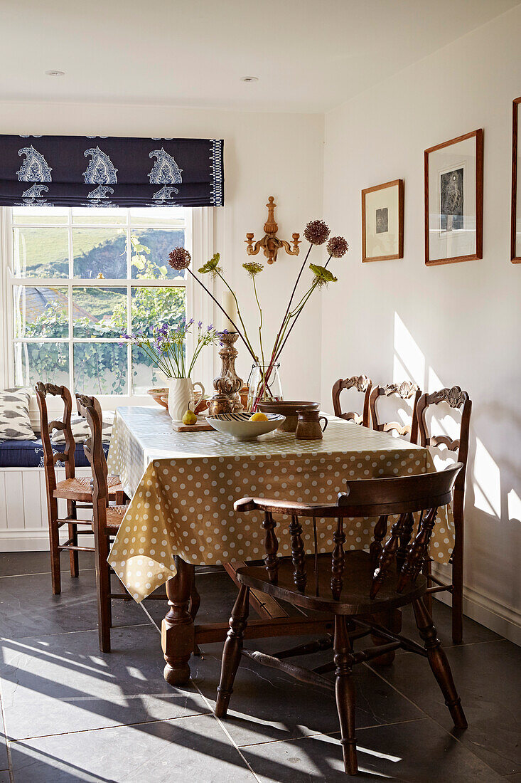Wooden chairs at sunlit table with spotty tablecloth in Port Issac beach house Cornwall