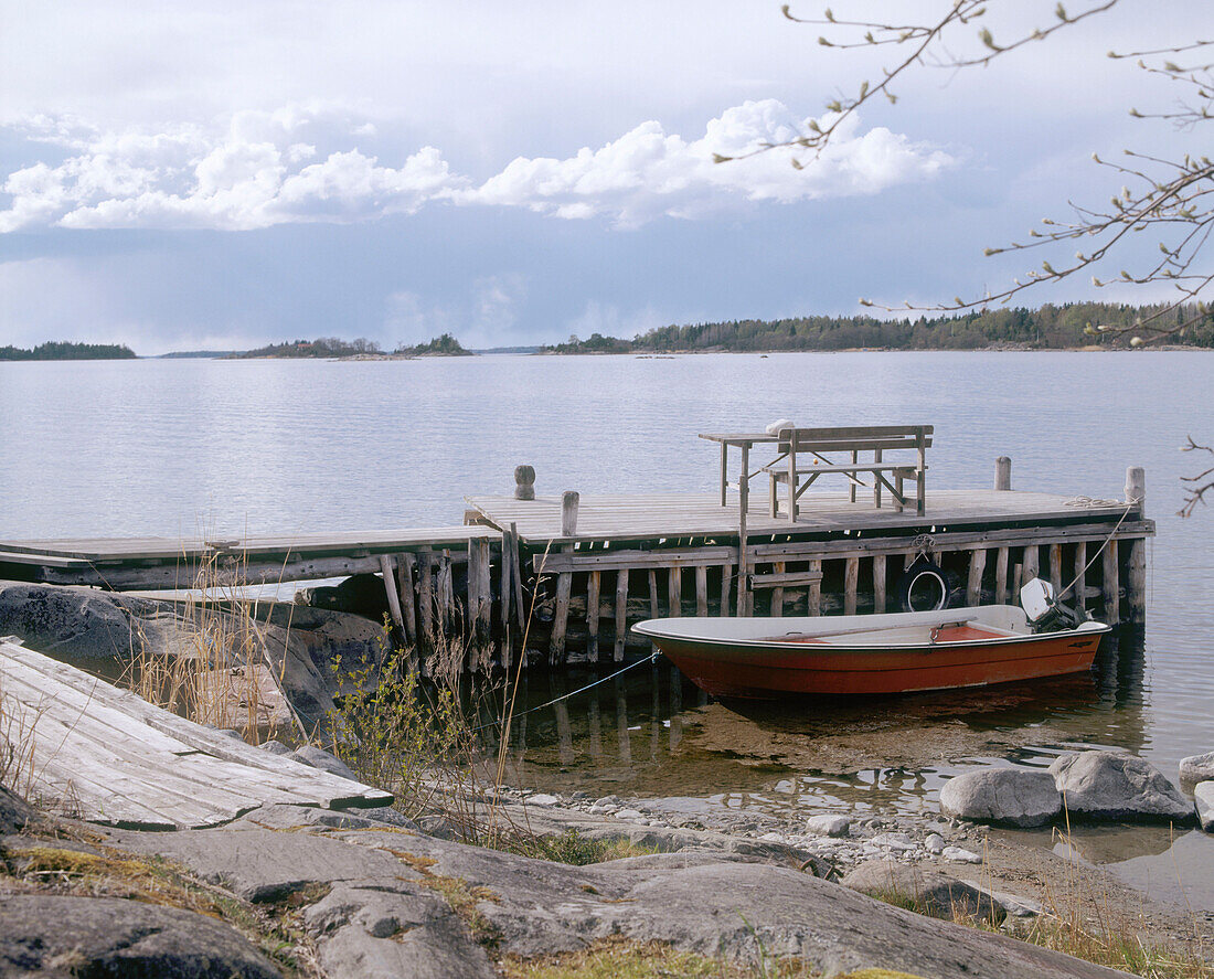 A landscape view of a lake with a boat moored to a wooden pier in the foreground