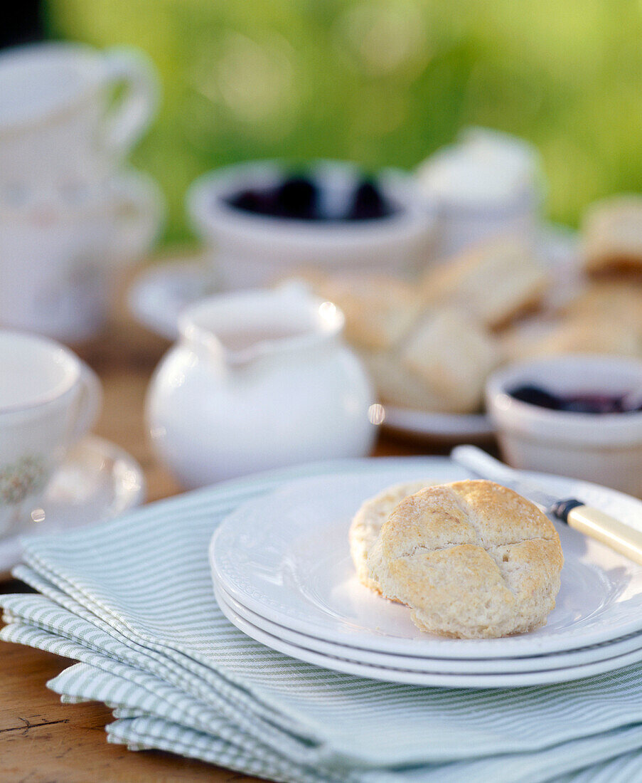 Gedeckter Frühstückstisch im Freien mit Brötchen, Geschirr und Stoffservietten