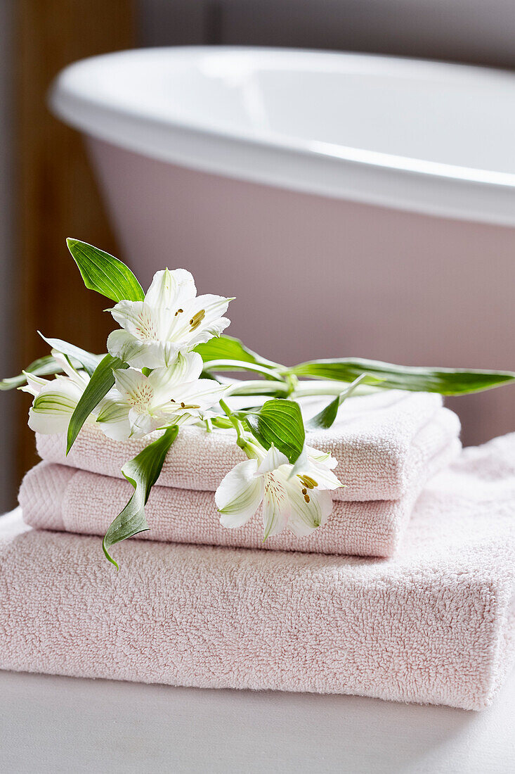 Cut lilies on folded towels in Kent farmhouse bathroom, UK