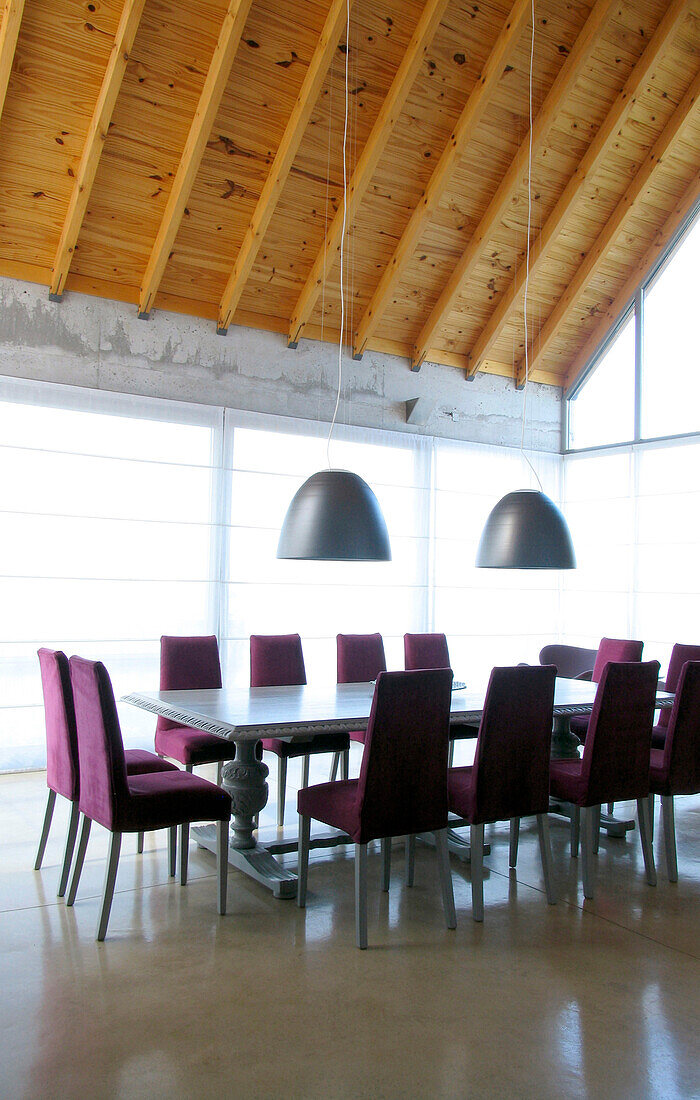 Dining room with antique oak table polished in grey with chair upholstered in violet courderoy with Italian lamp shades