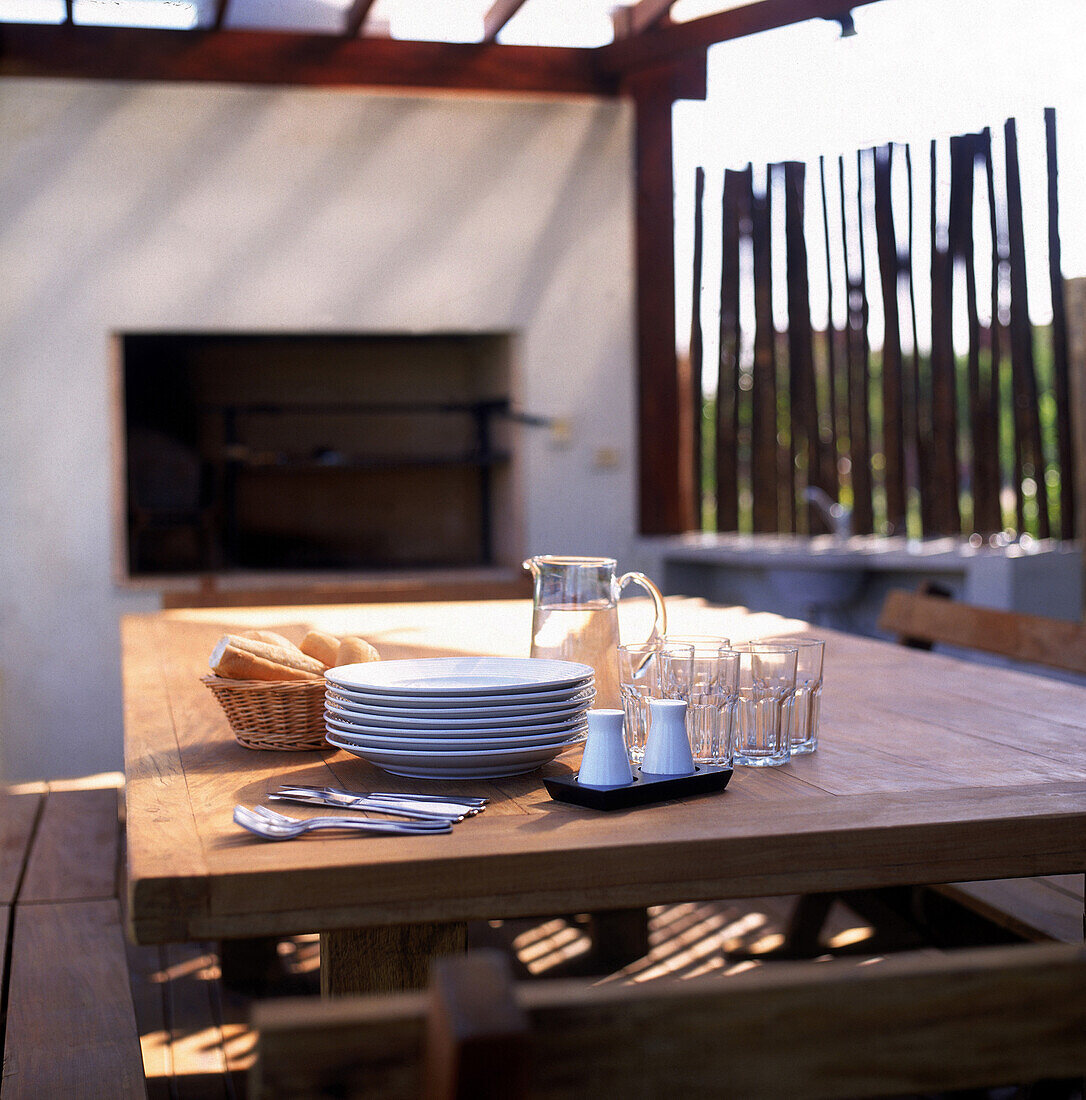 Grill area with tableware and wall of vertically set rustic logs