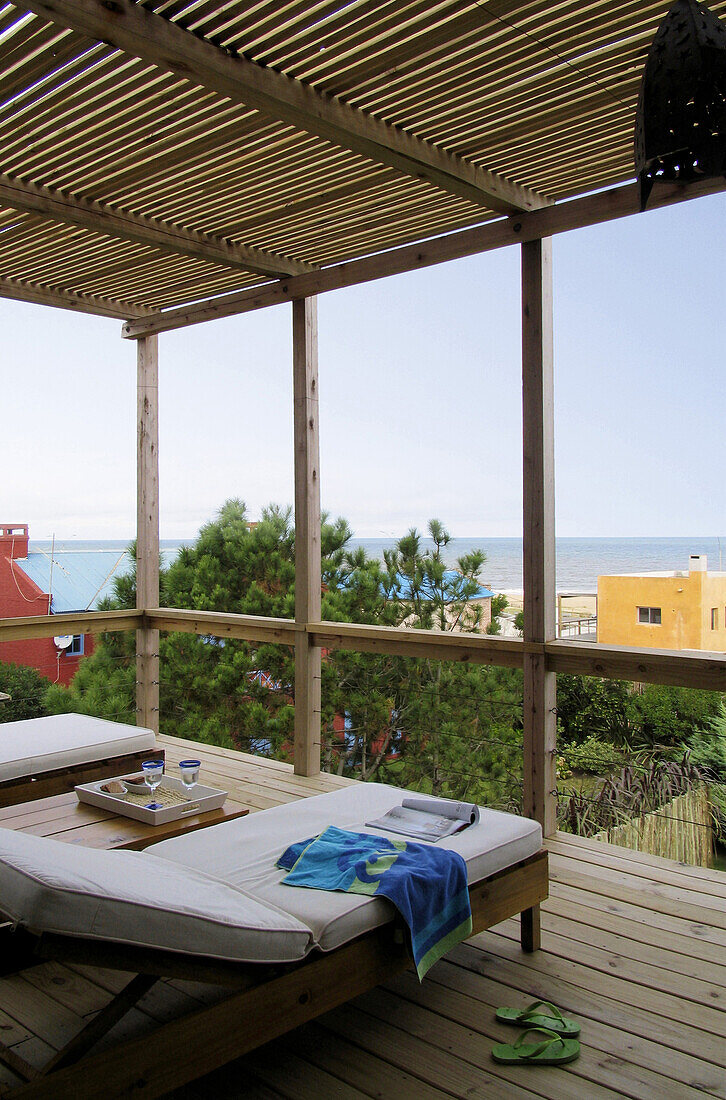 Sonnenliegen auf einem schattigen Balkon mit Blick auf das Meer