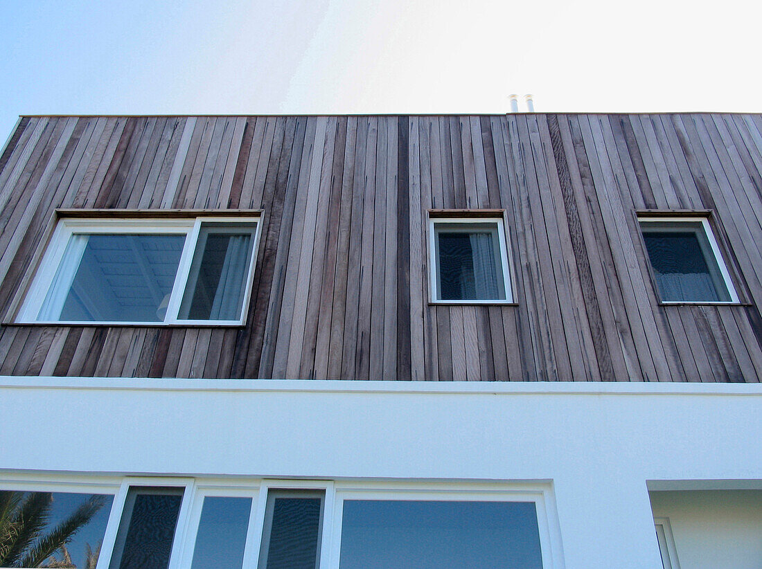 Windows of holiday home exterior with wood cladding