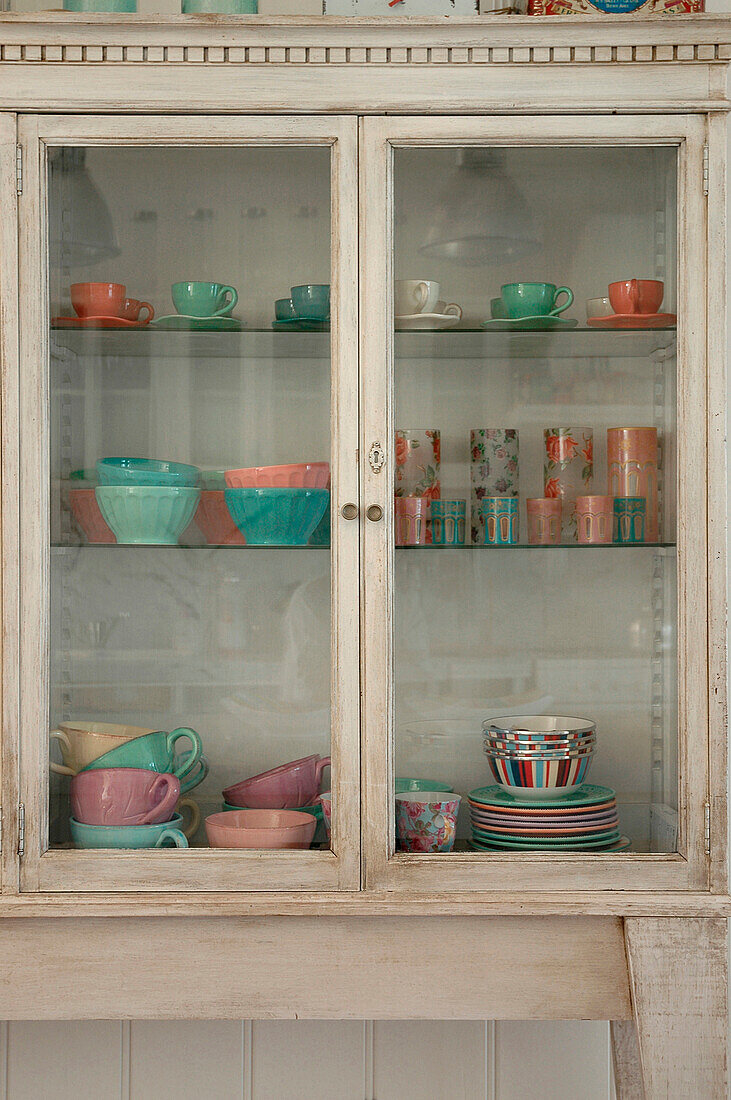 White painted kitchen dresser with pastel coloured glass tableware