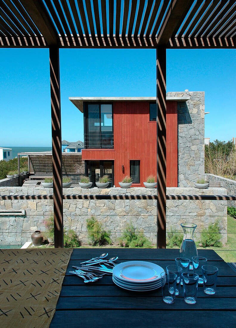 Geschirr auf einer schattigen Veranda mit Blick auf ein Strandhaus