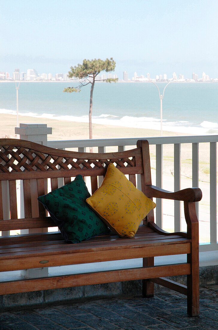 Wooden bench with cushions on coastal exterior balcony