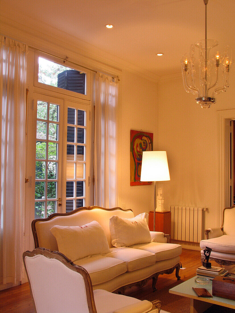 White three-piece suite in lit room with curtains and patio doors