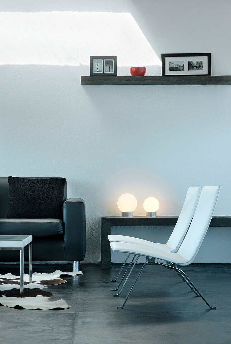 Matching chairs in living room with shelves and orb lamps on smoothed concrete floor