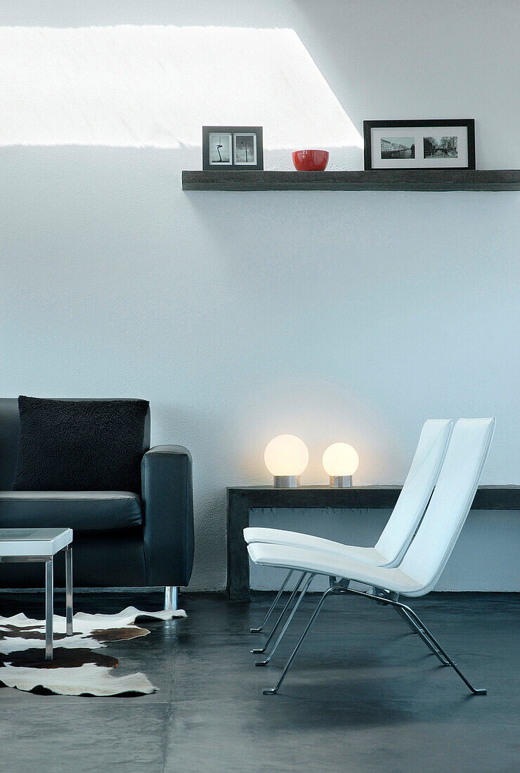 Zusammenpassende Stühle im Wohnzimmer mit Regalen und Kugellampen auf geglättetem Betonboden