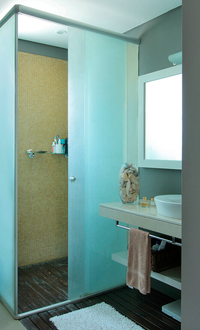 En-suite-Badezimmer mit Schmirgelglasscheibe, sandfarbenen venezianischen Kacheln und einer Marmorplatte mit weißen Keramikwaschbecken