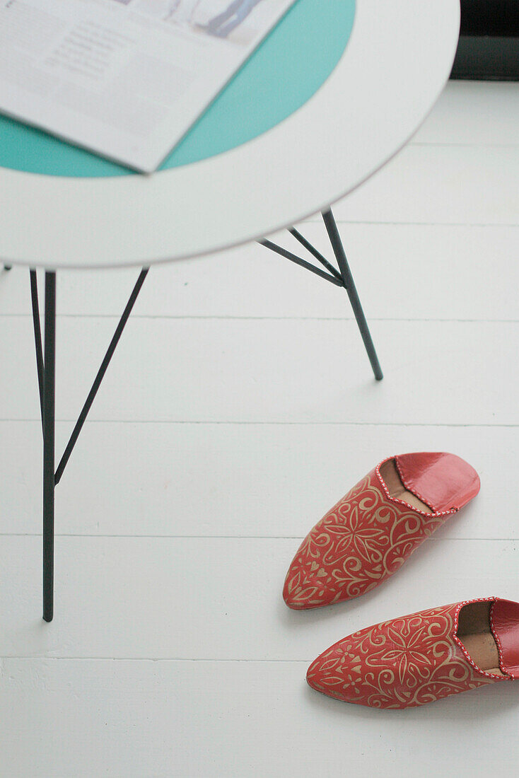 Red Indian slippers on painted floor under bedroom table