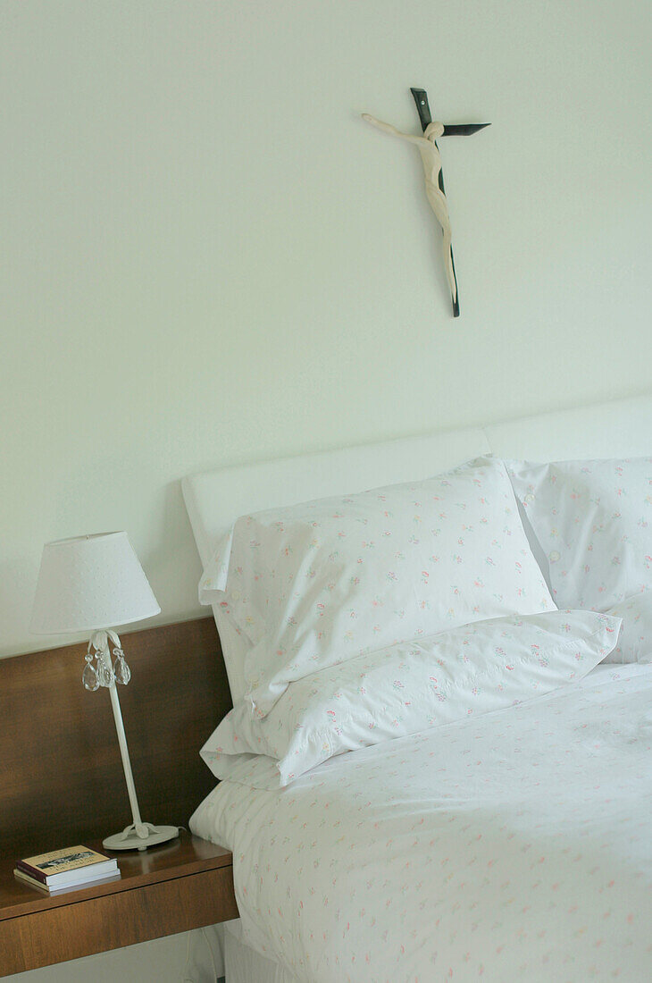 Pillows resting on headboard with lamp and book on bedside table