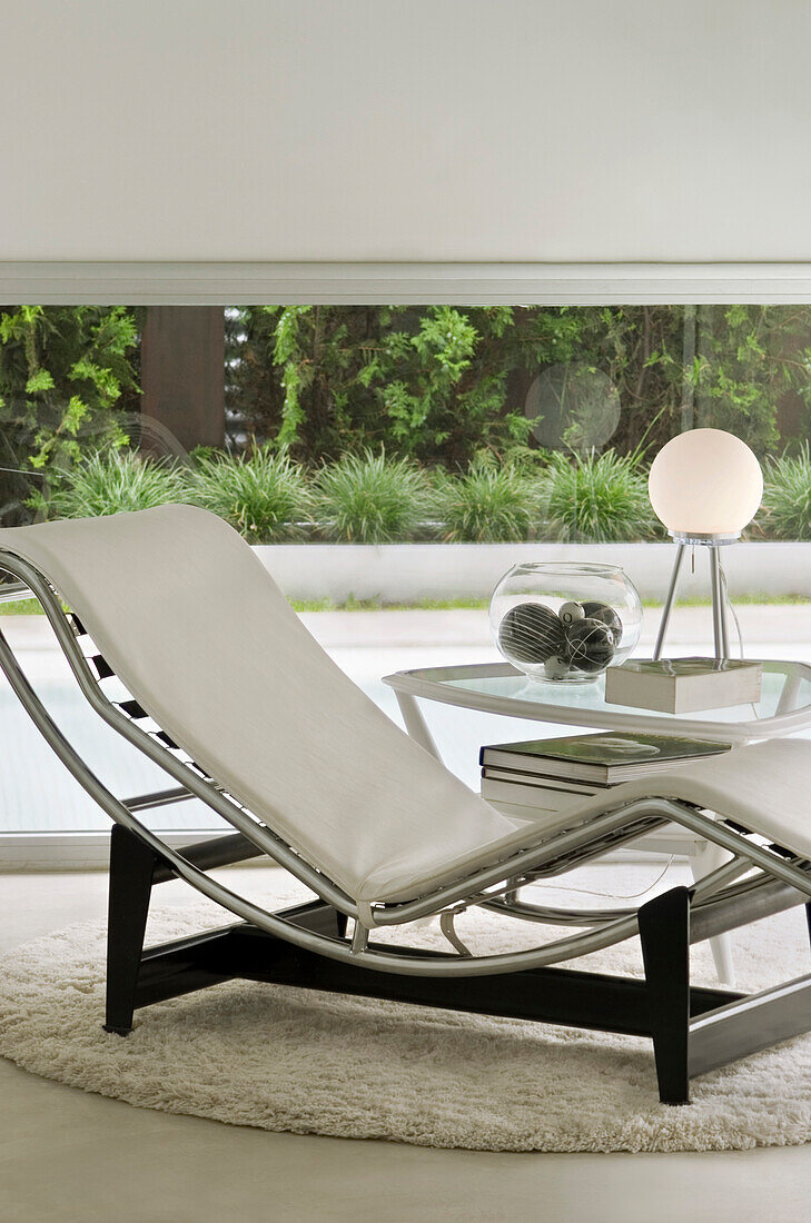 White leather recliner at window with garden view