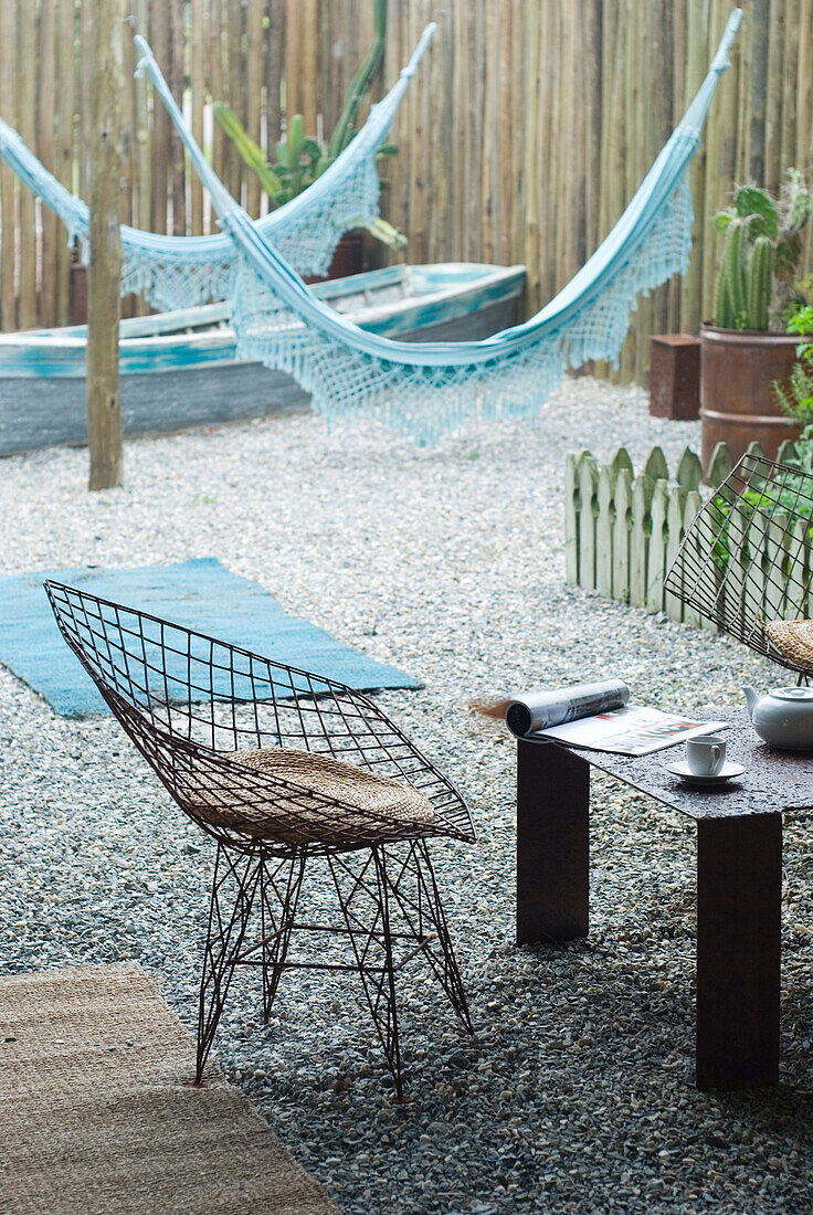 Metalworked chair in gravelled courtyard with two Paraguayan hammocks