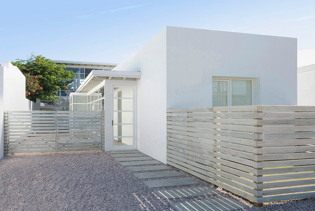 Whitewashed building exterior with fencing and gravel driveway