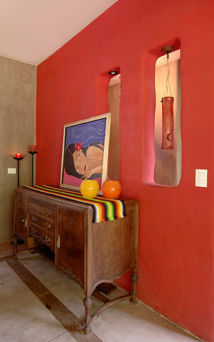 Wood dining-room sideboard with a typical Mexican runner; tall iron candelabra and a picture that adds colour