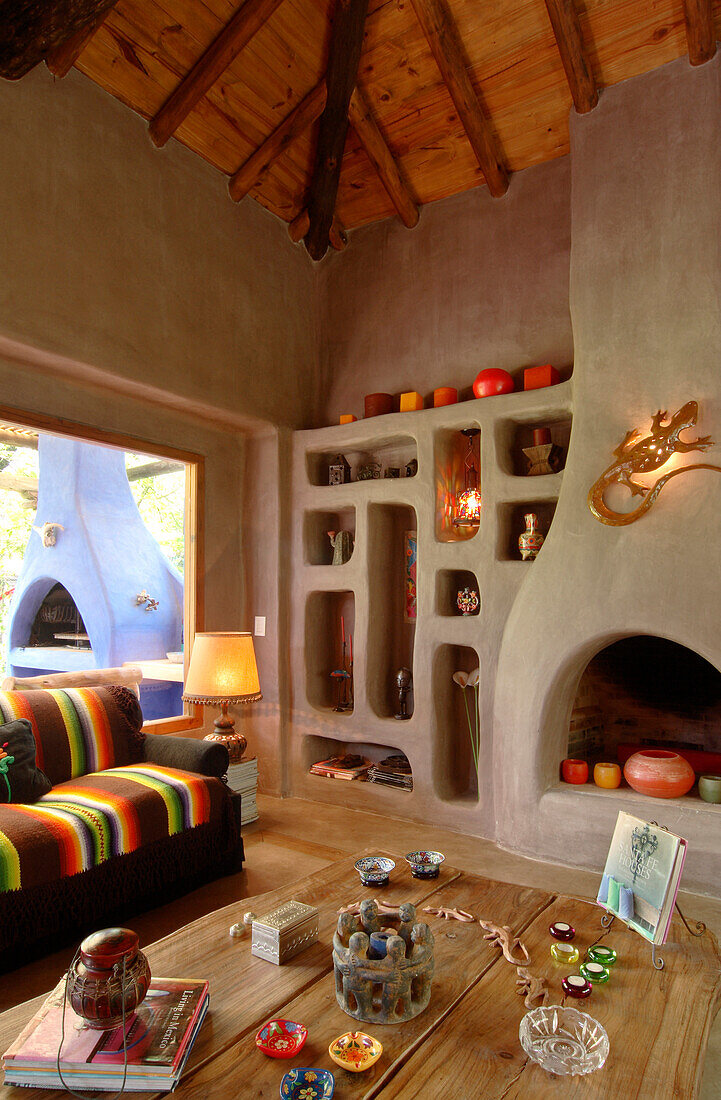 Living-room table with ornaments on oak boards and concrete niche shelving with fireplace resembling an old mud oven
