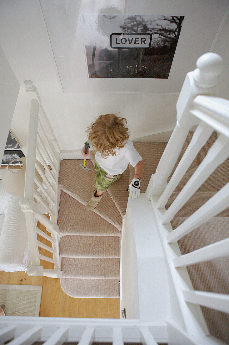 Blick von oben auf einen kleinen Jungen, der die Treppe hinuntergeht