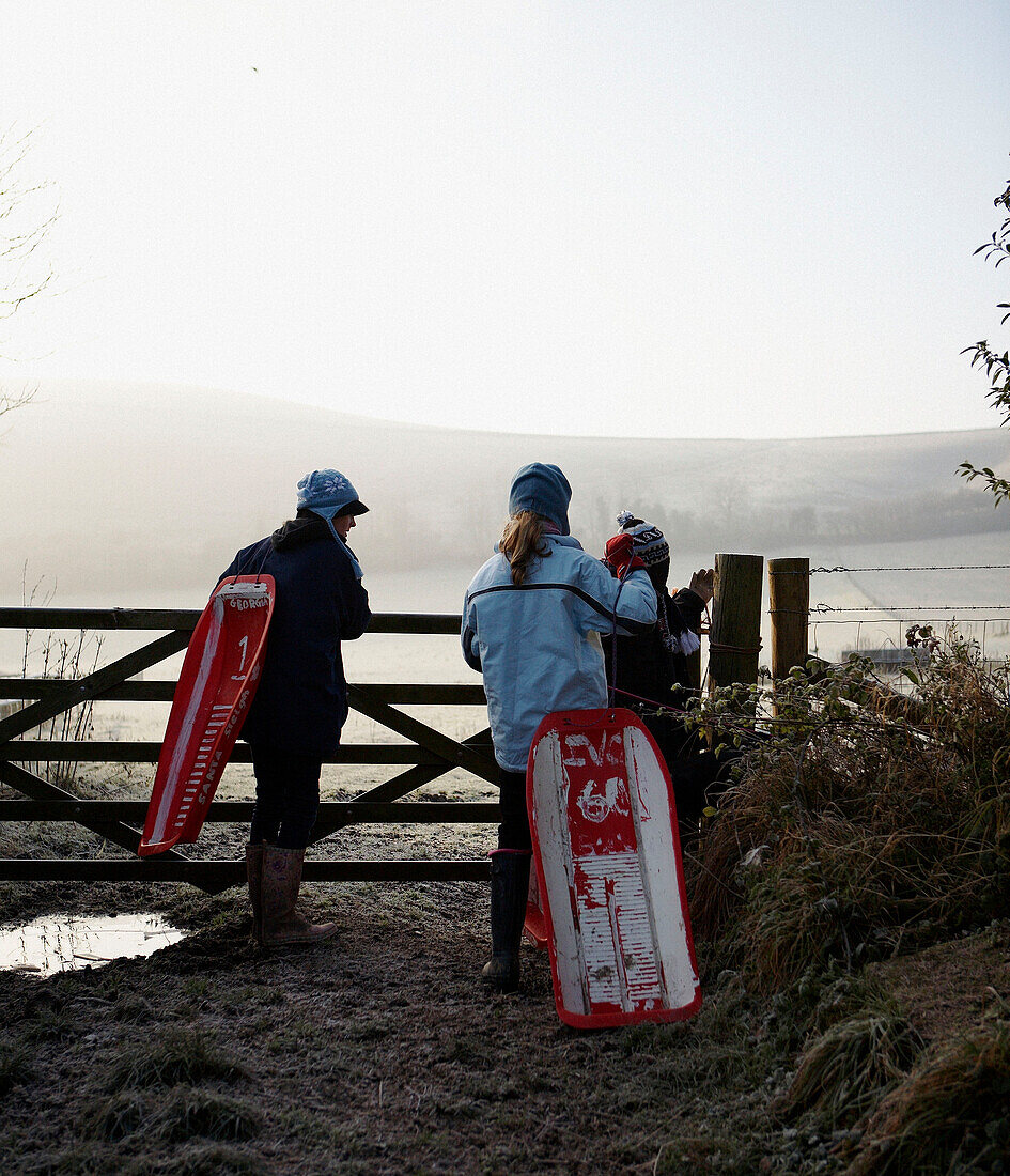 Children with sleds opening gate