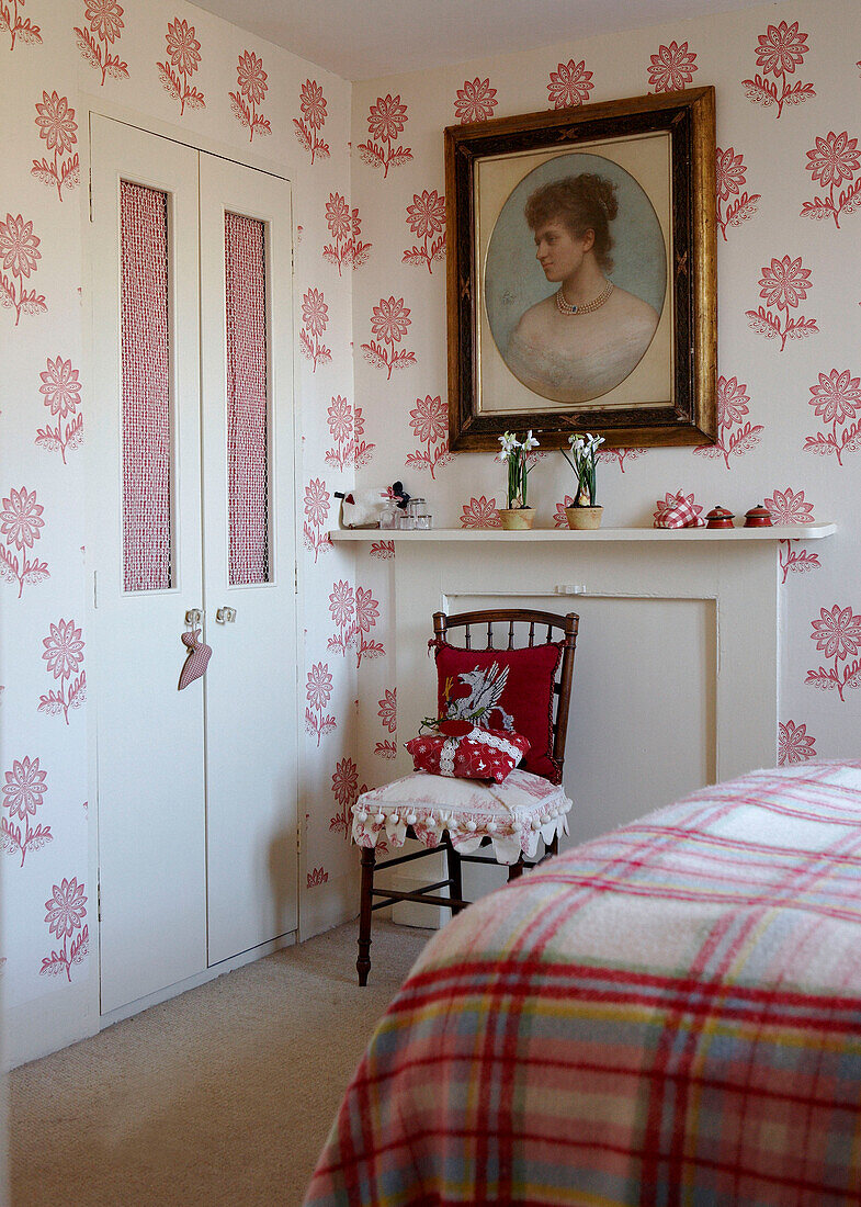 Checked blanket in bedroom with storage cupboard and portrait over fireplace